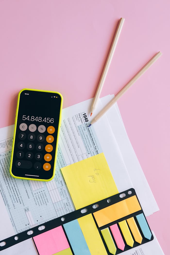 A vibrant workspace with a smartphone and tax documents on a pink background.